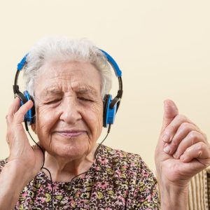 Vanha nainen kuuntelee musiikkia kuulokkeilla ja nauttii.