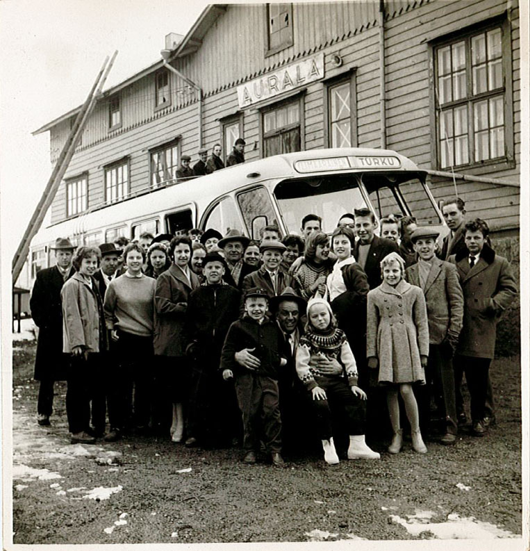 An old photograph of a group of people in front of a bus