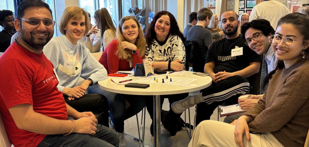 ihmisiset juttelevat pöydän ympärillä Auralan kielikahvilassa