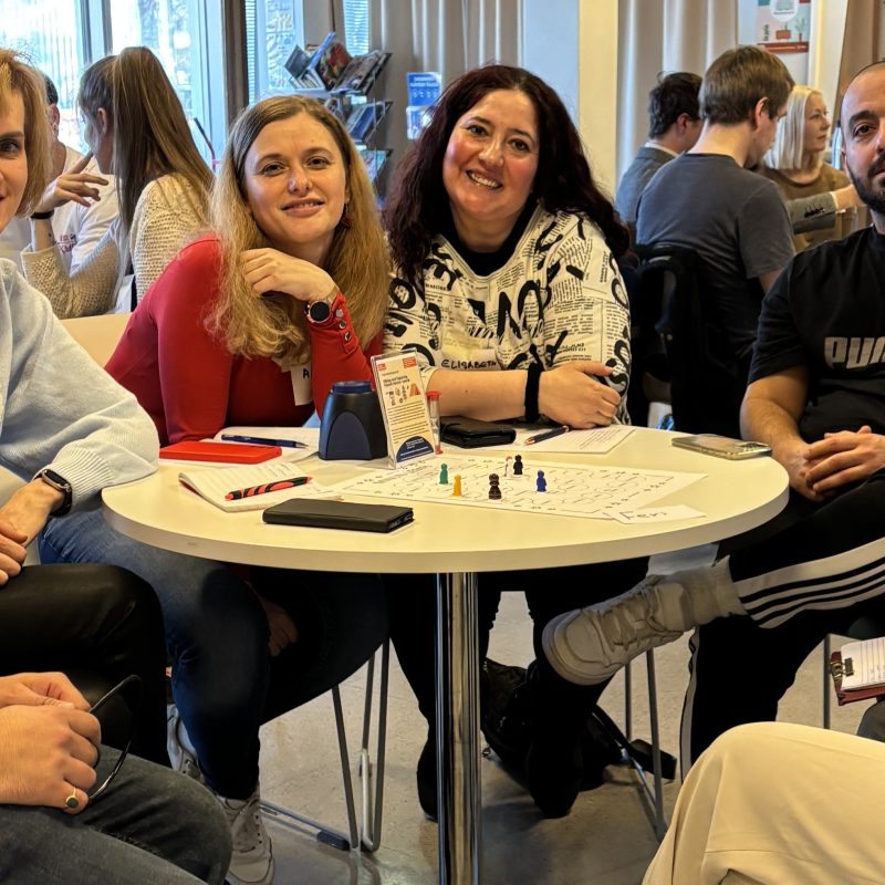 ihmisiset juttelevat pöydän ympärillä Auralan kielikahvilassa