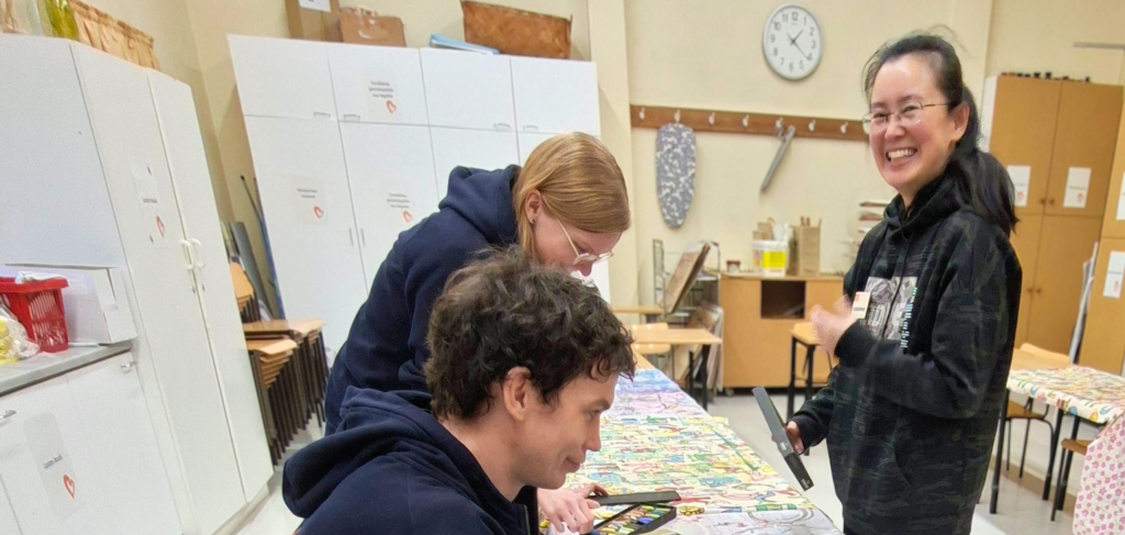 Kolmen ihmisen ryhmä puuhastelee työpöydän ääressä käsityöluokassa