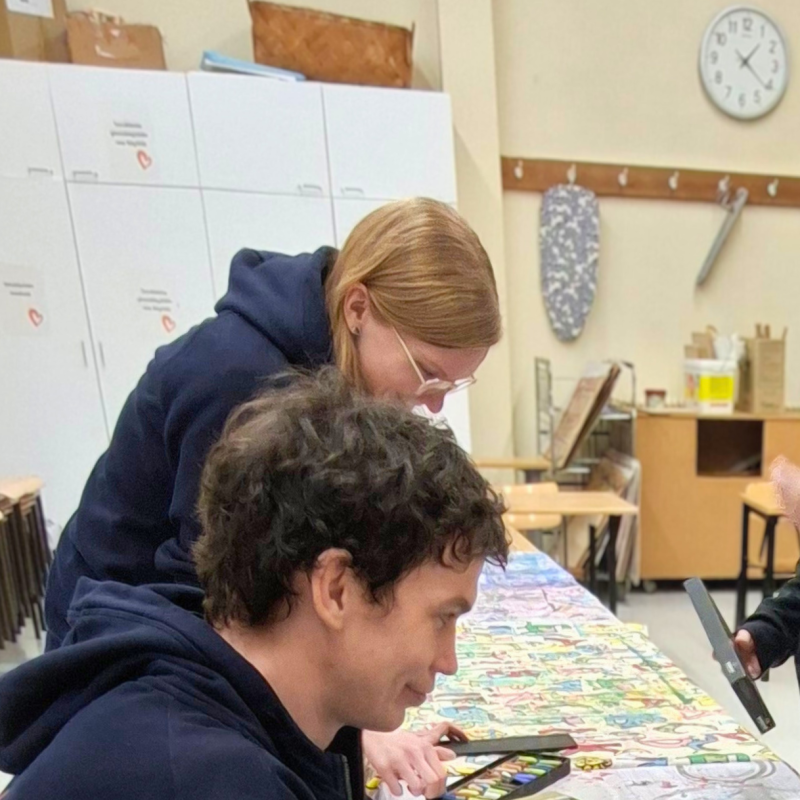 Kolmen ihmisen ryhmä puuhastelee työpöydän ääressä käsityöluokassa